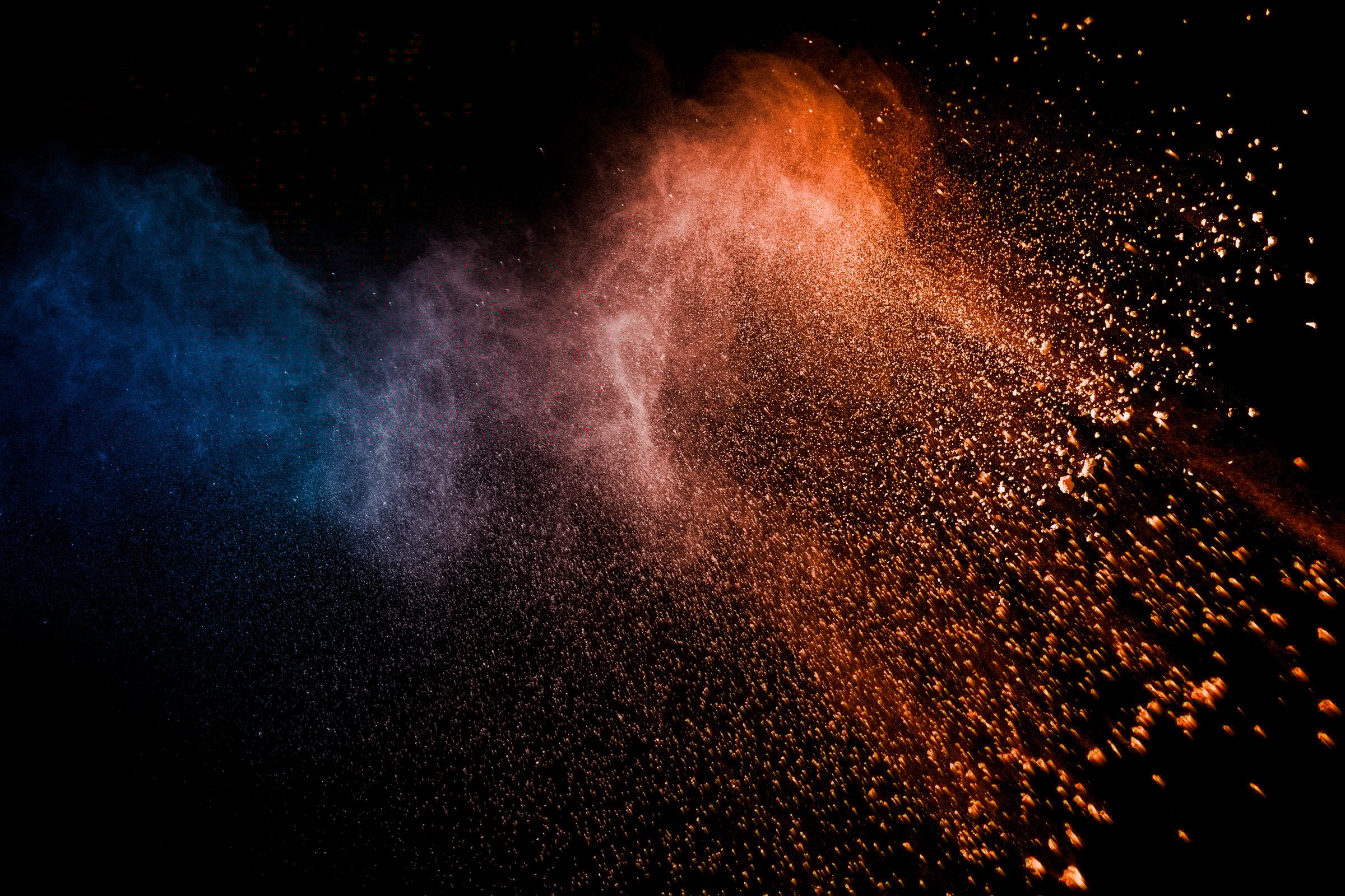 Orange blue powder explosion on black background.Orange blue color dust splash clouds.